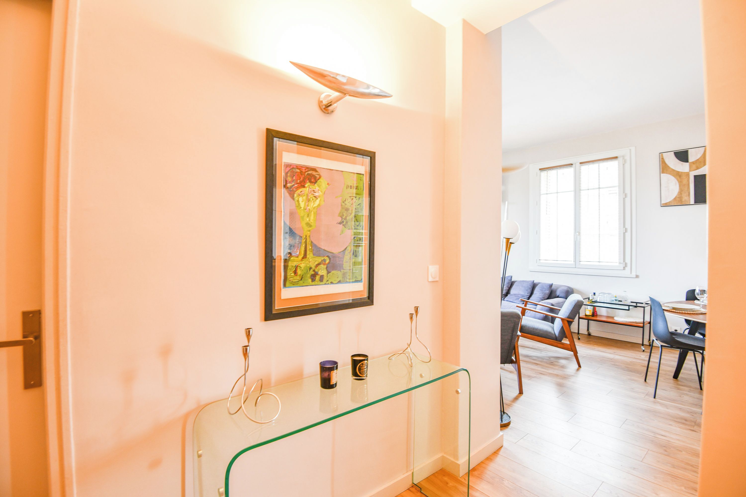 A modern interior with a glass partition, a framed artwork, and a dining area with a sofa and table.
