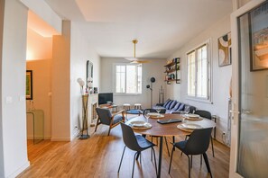 A modern dining area with a round table, chairs, and a television. - Bail mobilité - Vue sur le Panier - Balcon - 2 ch (Marseille)