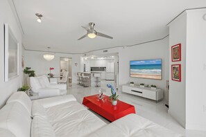 Ein modernes Wohnzimmer mit einem weißen Sofa, einem roten Couchtisch und einem Deckenventilator.
