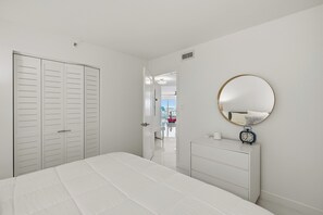 Ein Schlafzimmer mit Bett, Kommode, Spiegel und Kleiderschrank.