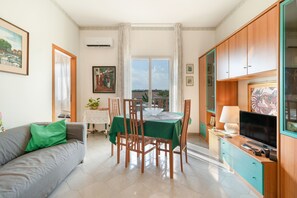 Un espacio habitable compacto con zona de comedor, sofá, televisión y vistas al exterior.