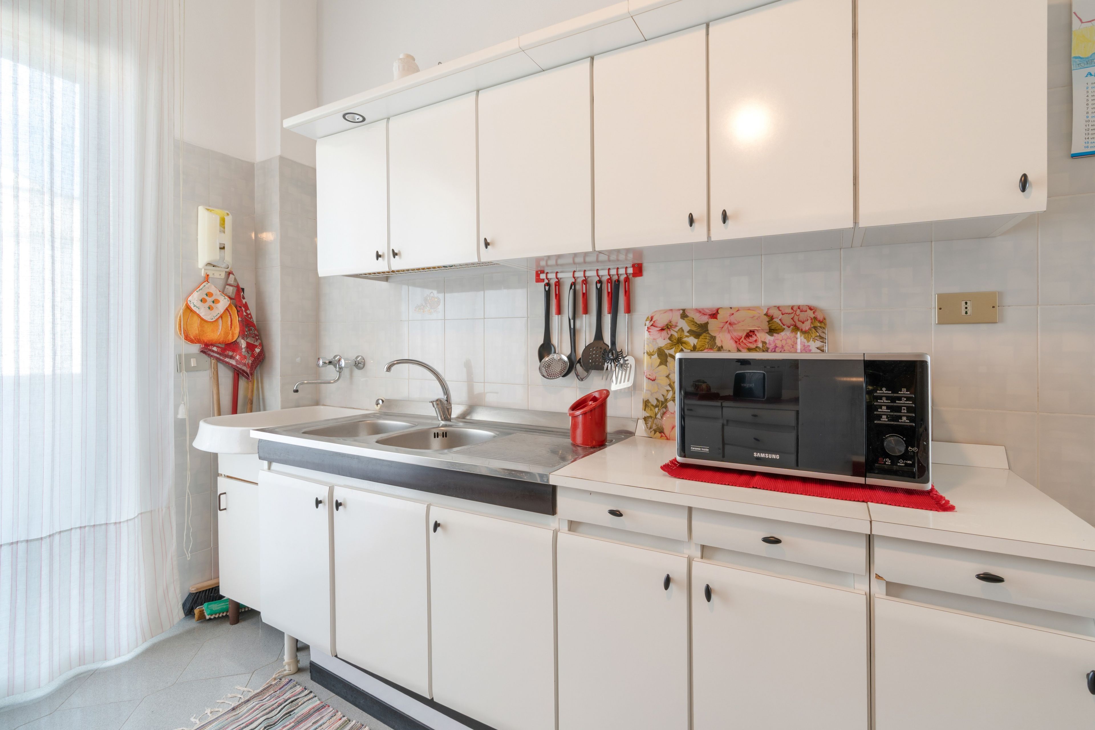 Una cocina moderna con gabinetes blancos, electrodomésticos de acero inoxidable y un microondas sobre la encimera.