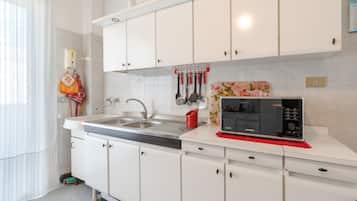 Una cocina moderna con gabinetes blancos, electrodomésticos de acero inoxidable y un microondas sobre la encimera.