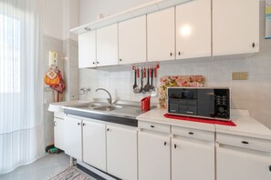 A modern kitchen with white cabinets, stainless steel appliances, and a microwave on the counter.