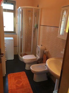 A bathroom with a shower enclosure, two toilets, a sink, and a window. - MareMilia Home Apartment with Balcony and Air Conditioning (Calabernardo)