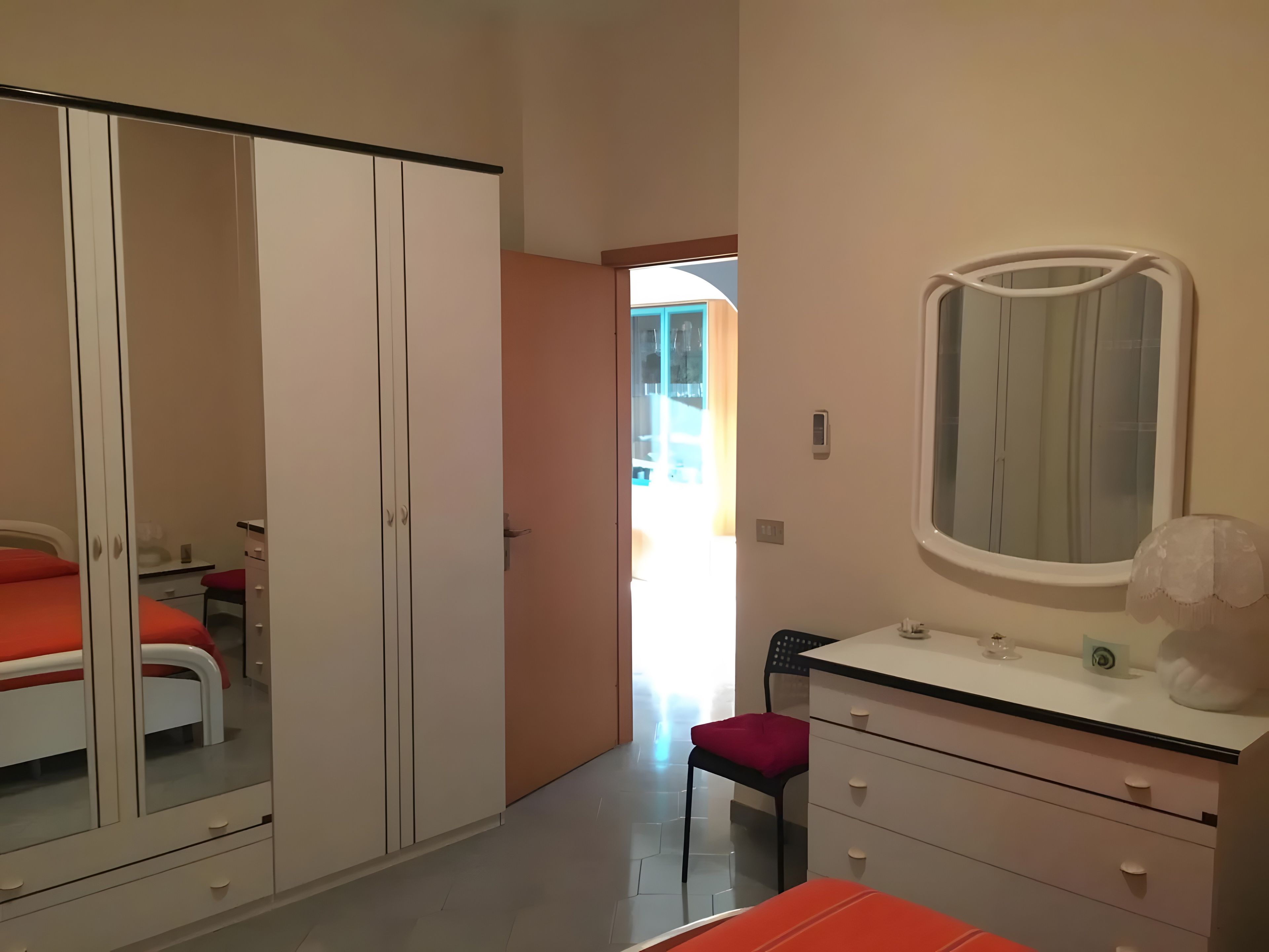 Een slaapkamer met een kledingkast, een bed, een bureau en een stoel.