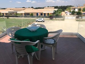 A terrace with a table and chairs, a view of the surrounding area, and a parked car. - MareMilia Home Apartment with Balcony and Air Conditioning (Calabernardo)