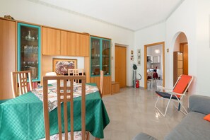 A dining area with wooden cabinets, a table with chairs, and a kitchen visible through an archway.