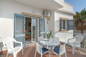 An outdoor balcony with a table, chairs, and a potted plant.