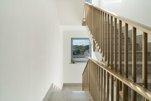 A staircase with a view of a garden through a window.
