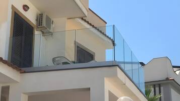 Een woongebouw met een balkon, een trap en een heldere lucht.