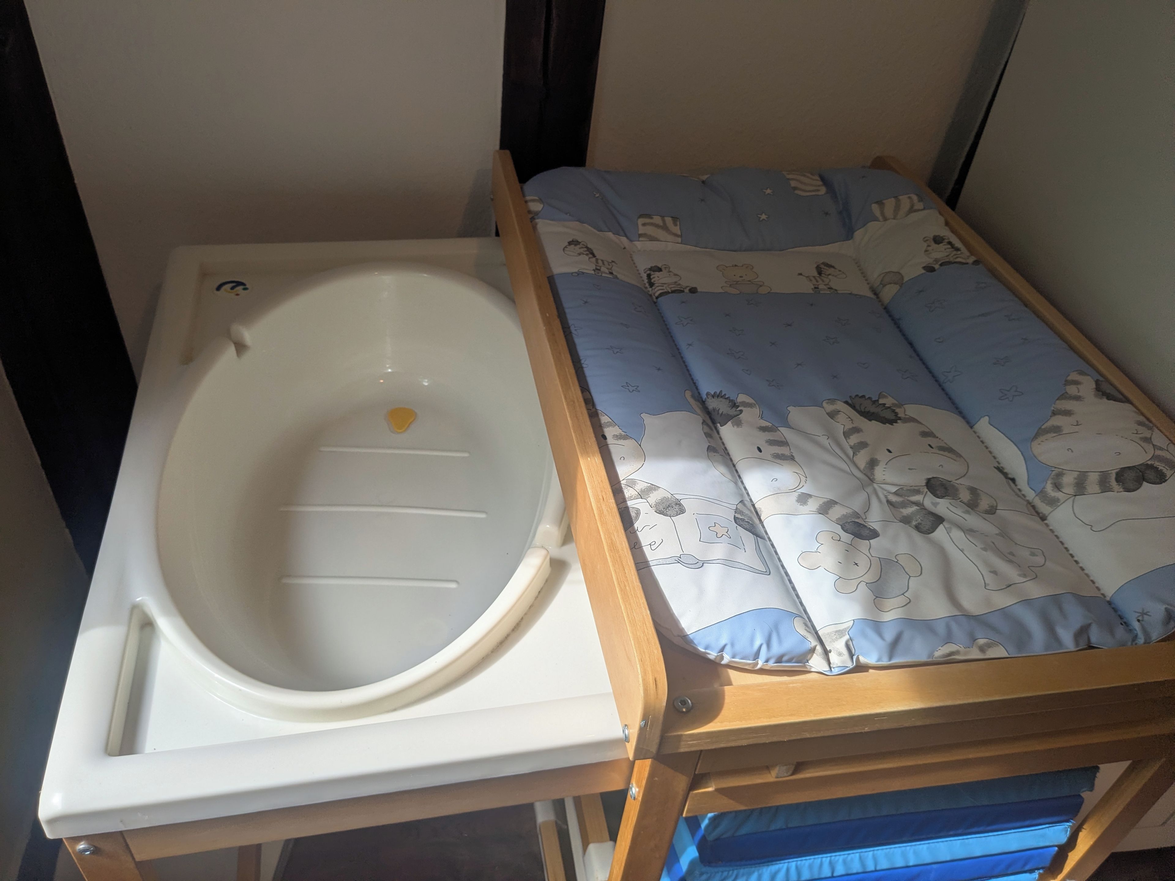 Une petite pièce avec une baignoire blanche et un lit doté d’un matelas à motifs bleus et blancs.