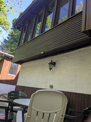 En bygning med facade, et vindue, en vægmonteret lampe og et bord med stole.