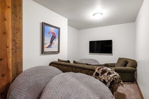 Ein Zimmer mit großem Fenster, einem an der Wand befestigten Flachbildfernseher und Holzboden.