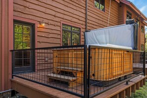 Eine Holzterrasse mit Whirlpool und einem Metallzaun.