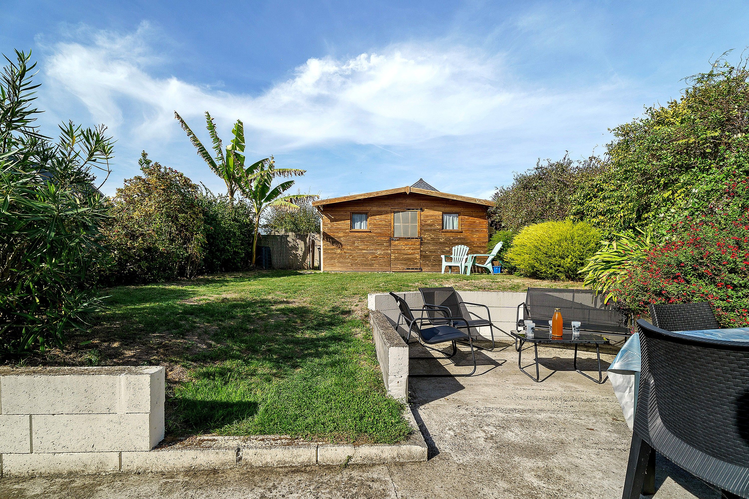 A wooden house with a patio area, outdoor furniture, and a garden.