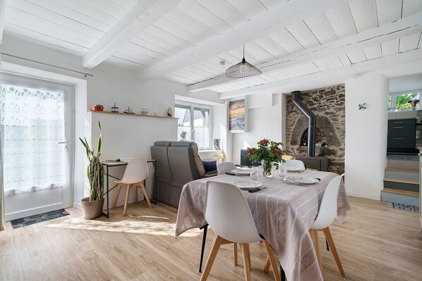 Un área de comedor con una mesa lista para dos personas, un sofá y una pared de piedra con chimenea.