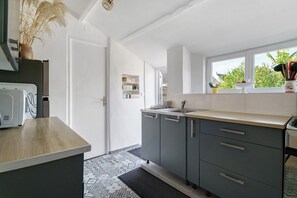 A modern kitchen with grey cabinets, a wooden countertop, and a window with a view of greenery.