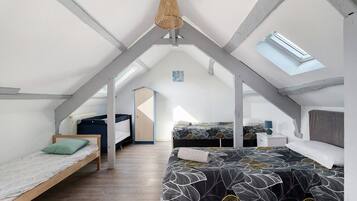 A loft bedroom with a sloped ceiling, a skylight, and a bed with a leaf-patterned bedspread.