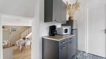 Cocina compacta con microondas, cafetera y armarios.
