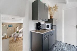 Cocina compacta con microondas, cafetera y armarios.