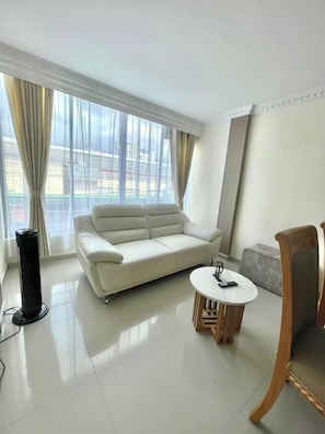 Una sala moderna con un sofá blanco, una mesita redonda y una silla.