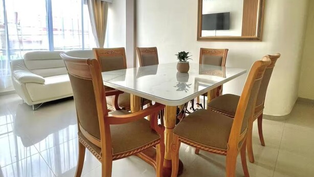 Uma sala de jantar com uma mesa redonda, seis cadeiras, um sofá e uma janela grande.