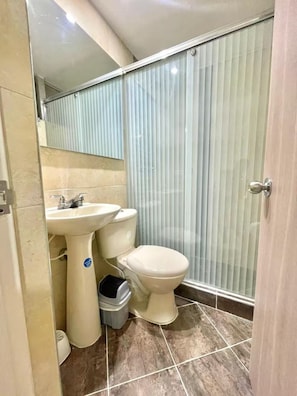 Un baño con inodoro, lavamanos y un cubo de basura.