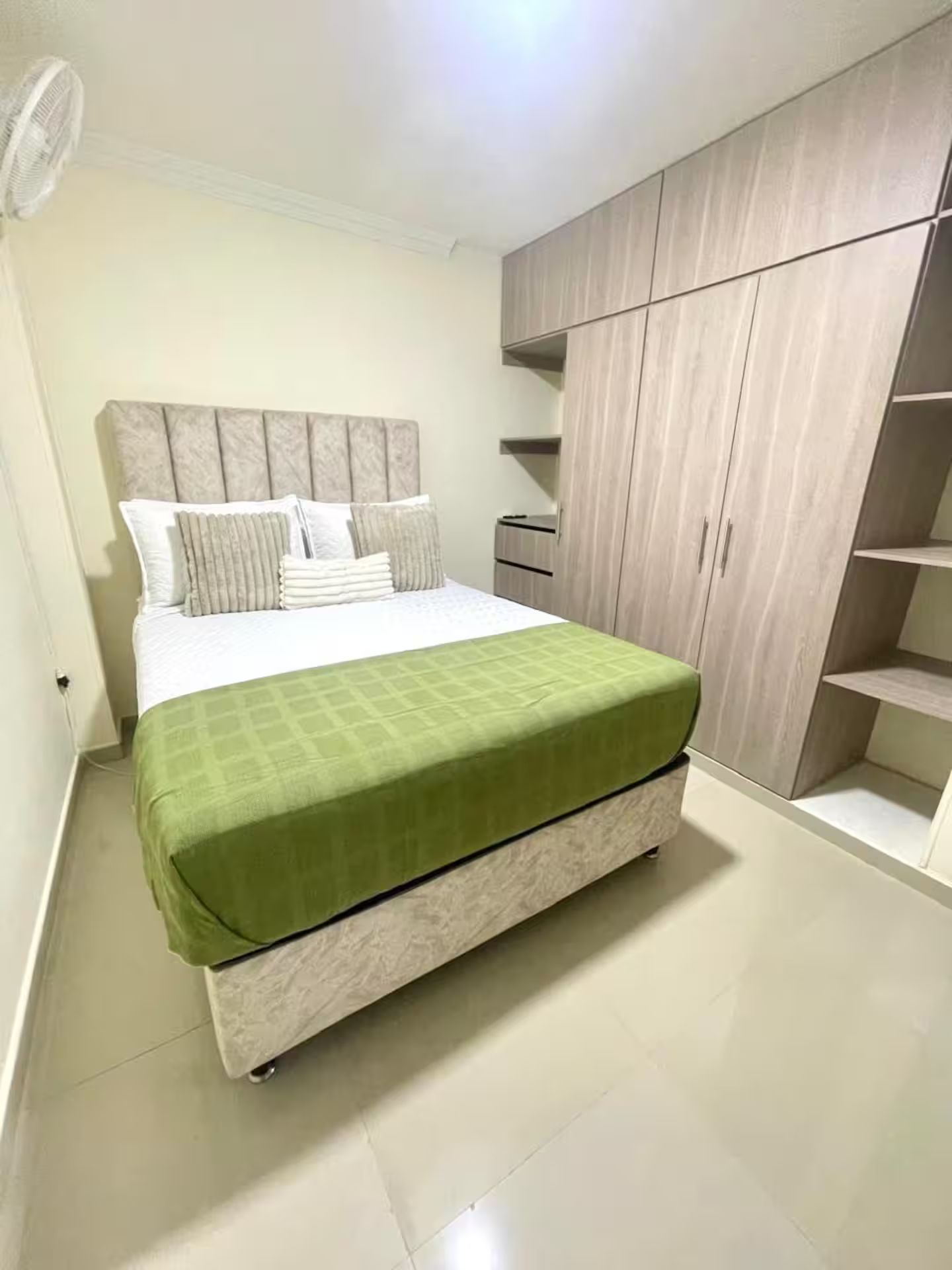 Ein Schlafzimmer mit einem Bett, einer grünen Bettdecke, einem Kopfteil und fest installierten Holzbögen.