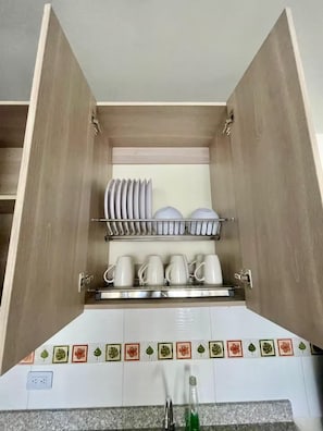Un armario de cocina con estantes que contienen platos, tazones y tazas.