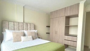 Quarto com uma cama, um guarda-roupa e uma mesa de cabeceira.