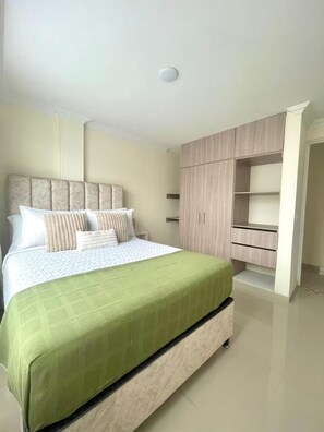 Un dormitorio con cama, armario y mesita de noche.