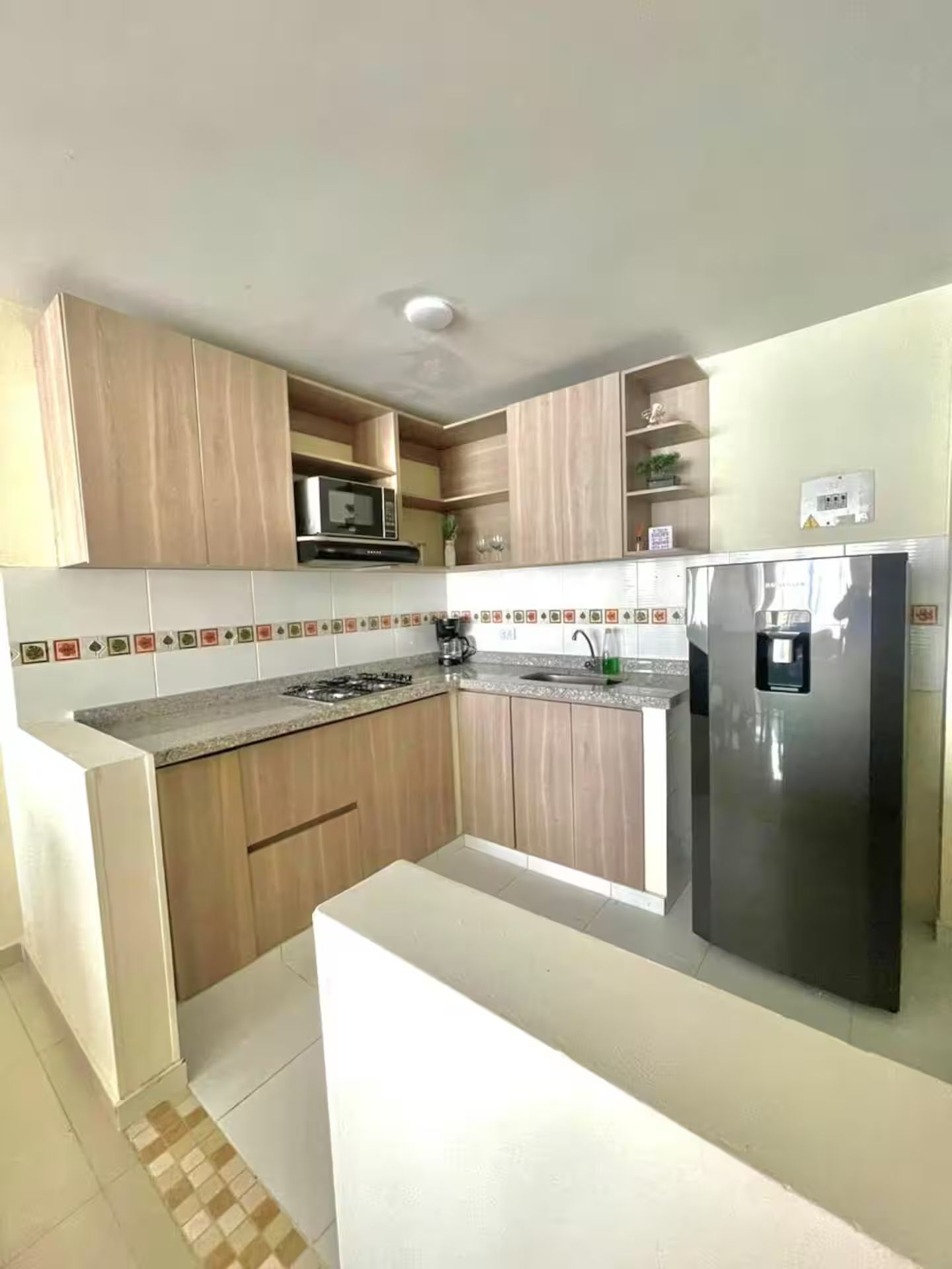 A modern kitchen with wooden cabinets, a stainless steel refrigerator, and a tiled backsplash.