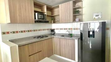 A modern kitchen with wooden cabinets, a stainless steel refrigerator, and a tiled backsplash.