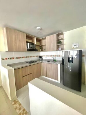 Una cocina moderna con armarios de madera, un refrigerador de acero inoxidable y un respingo de azulejos.