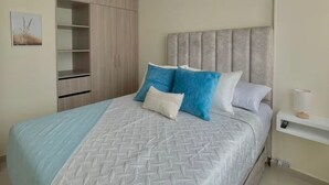Une chambre à coucher comprenant un lit, une tête de lit, une armoire et une table de chevet.