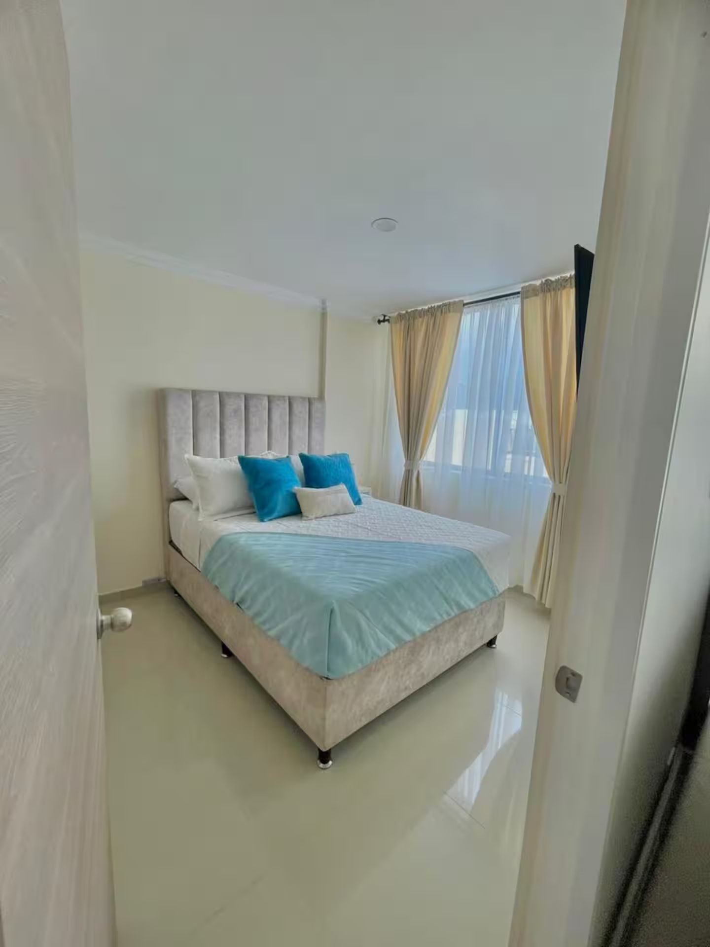Ein Schlafzimmer mit Bett, Vorhängen und einer Tür.
