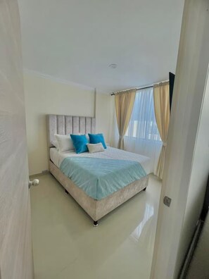 Um quarto com cama, cortinas e porta.