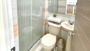 Une petite salle de bain comprenant des toilettes, un lavabo et une petite plante en pot.
