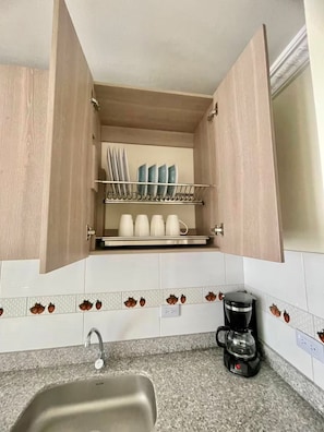 Una cocina con lavavajillas integrado, cafetera y un soporte para utensilios.