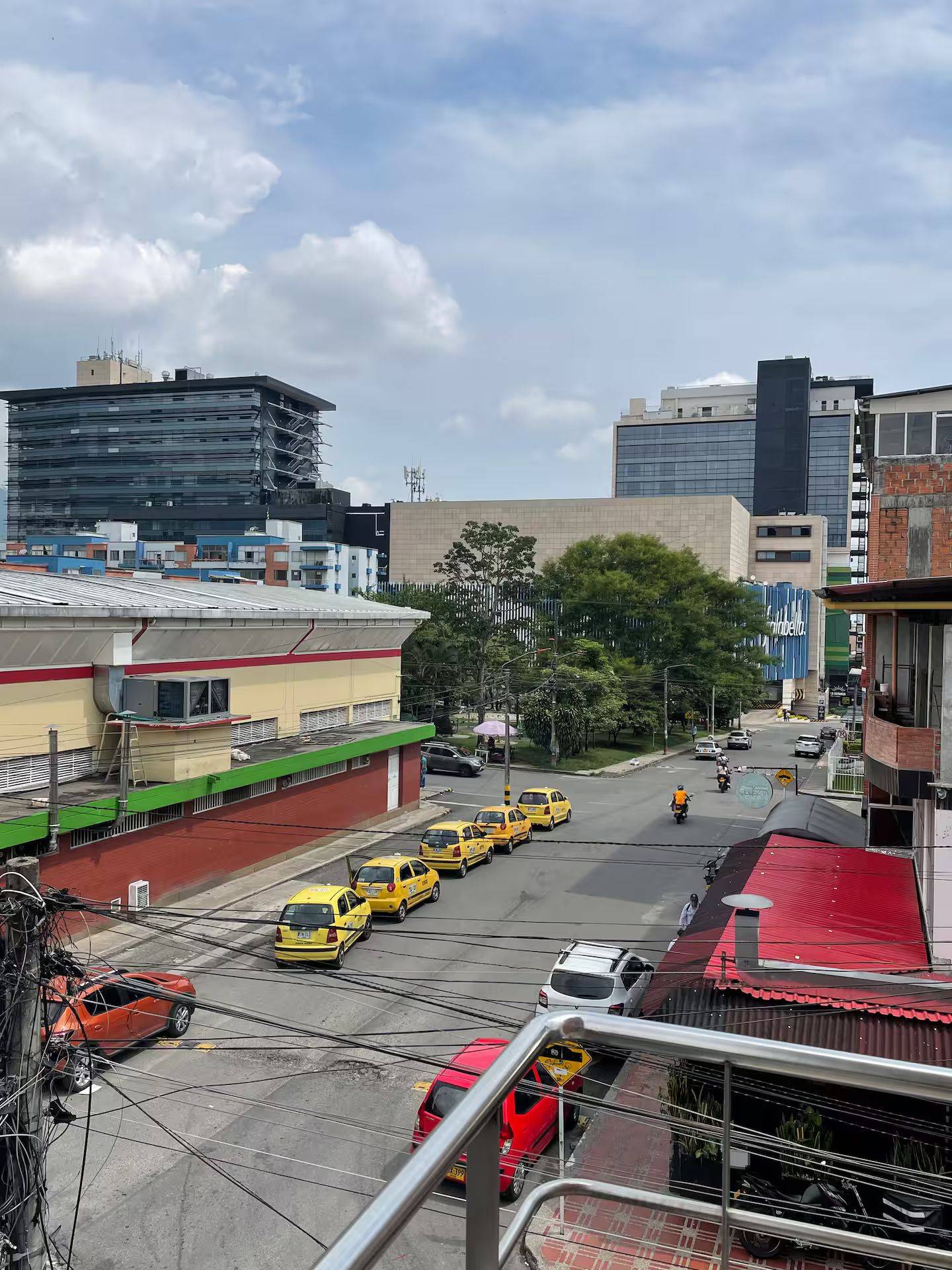 A city street with buildings, a red car, and yellow taxis.