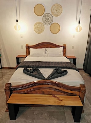 A bed with a wooden frame, a white mattress, and a gray blanket. There are two bedside tables with lamps.