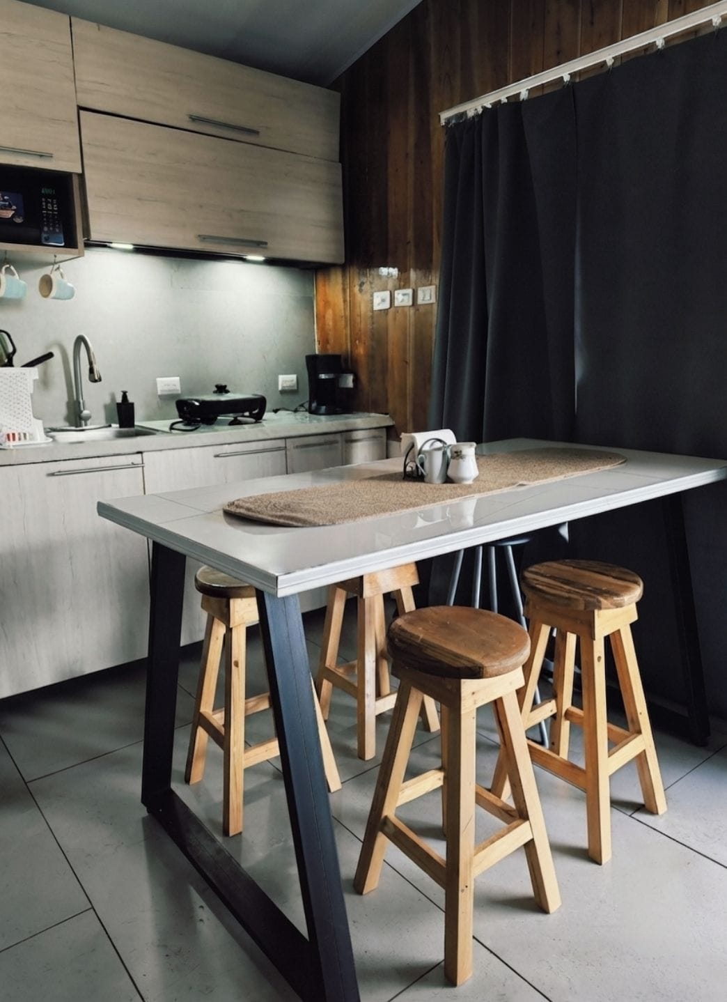 Una cocina moderna con una isla central, taburetes de madera y una cafetera.