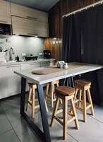 A modern kitchen with a central island, wooden stools, and a coffee machine.
