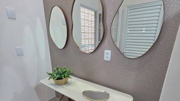 A hallway with a white console table, a potted plant, and three wall-mounted mirrors.