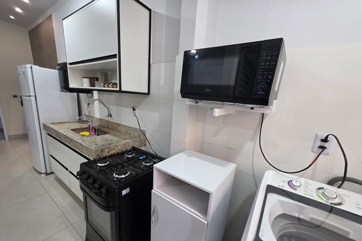 A compact kitchen with a gas stove, a microwave, and a built-in washing machine.