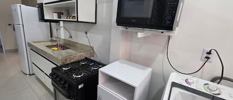 Cocina compacta con estufa a gas, microondas y lavadora integrada.