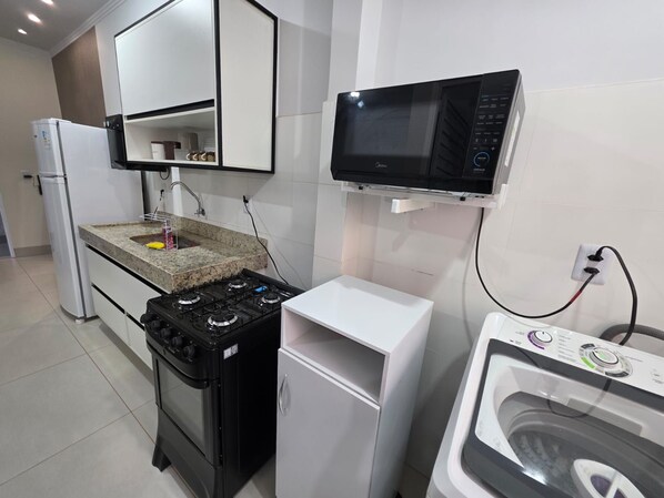 A compact kitchen with a gas stove, a microwave, and a built-in washing machine.