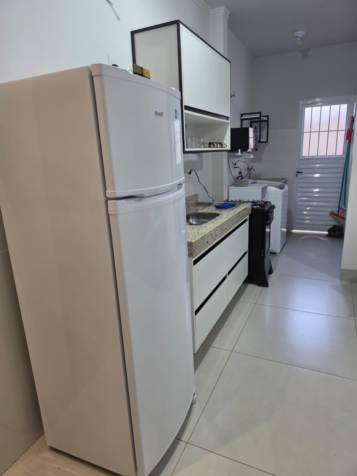 A kitchen with a white refrigerator, a countertop with a sink, and cabinets above.
