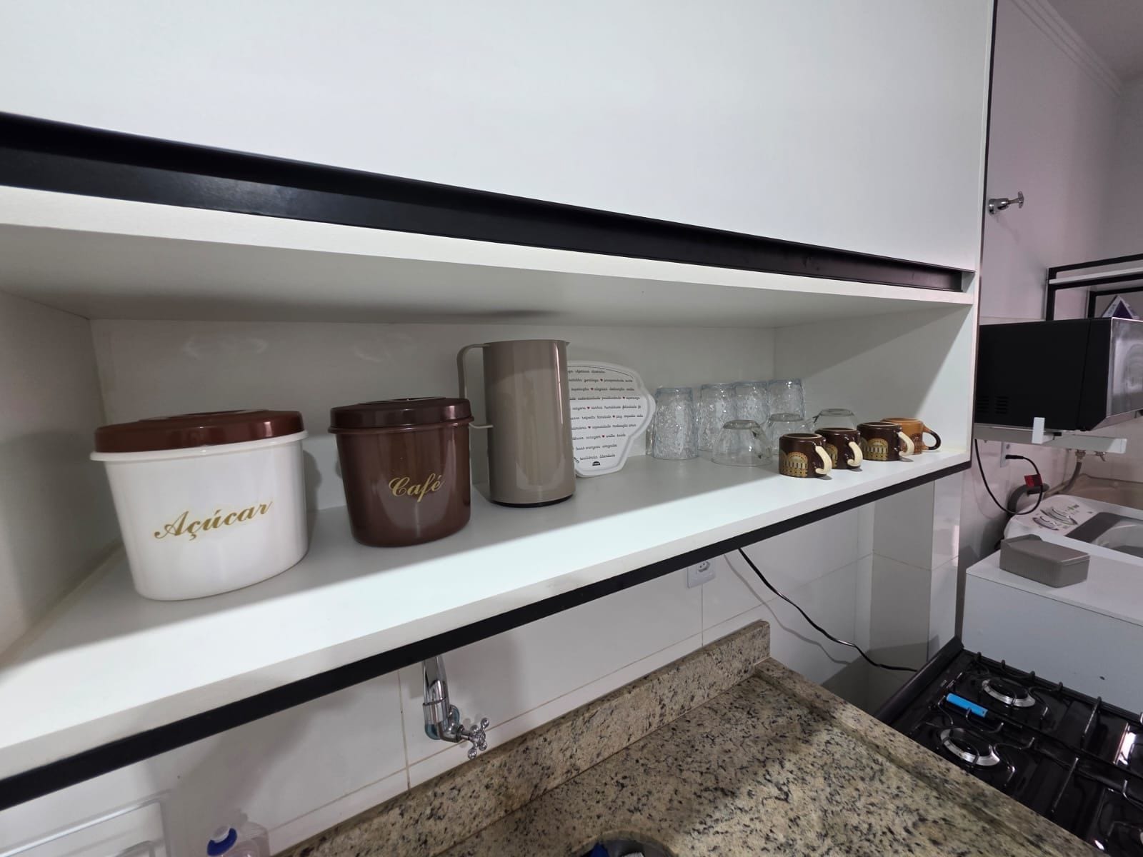 A kitchen shelf with various containers and mugs.